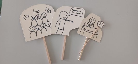 Drei Sprechblasen aus Holz mit Zeichnungen und Sprüchen liegen auf einem Tisch