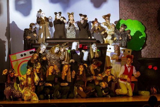 Abschlussszene auf einer Bühne mit Schüler/innen als Katzen verkleidet.