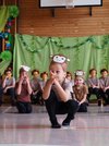 Kinder mit einem Stirnband mit einer Affenmütze hocken am Boden und haben die Hände vor dem Gesicht.