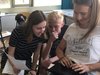 Foto von zwei Schülerinnen und einem Schüler mit ausgedruckten Unterlagen und einem Netbook