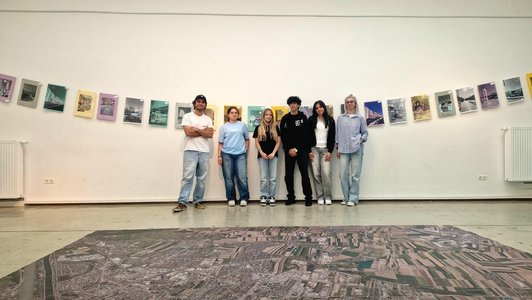 Schüler/innen stehen vor ihren Fotografien, die an der Wand hängen