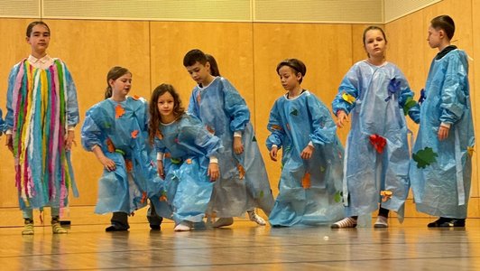 Kinder in blauen Regengewändern schauspielen