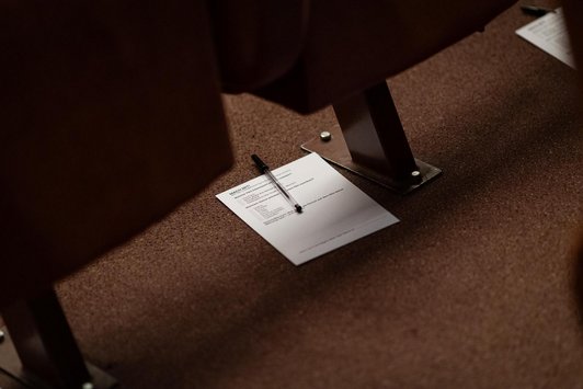 Zettel und Stift auf Boden unter Kinositzen