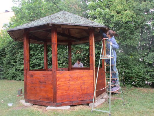 Foto von zwei Schülerinnen, die einen Pavillon im Garten bemalen