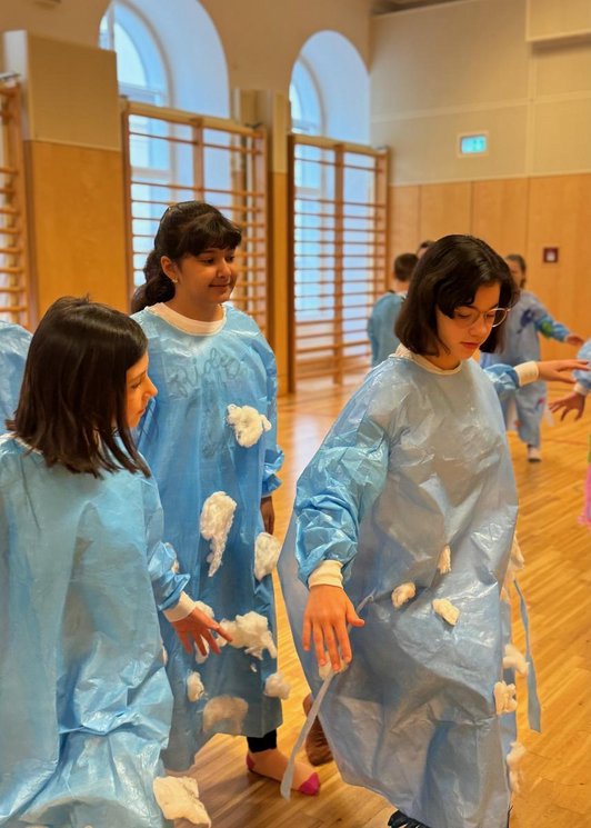 Kinder in blauen Regengewändern schauspielen