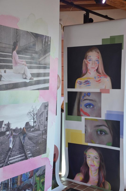 zwei Plakatrollen mit Fotos von Mädchen die im Gesicht, Hals und Schulter bemalt sind , sowie Fotos von Mädchen auf den Gleisen  und auf eines auf Stufen sitzend.