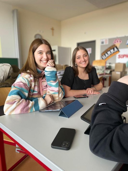 Schüler/innen sitzen in Raum mit Kunstwerken an der Wand