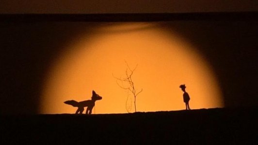 Ausschnitt aus einem Schattentheater, es zeigt einen Fuchs, einen Baum und einen kleinen Jungen.