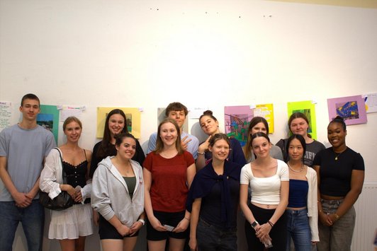 Schüler/innen stehen vor ihren Fotografien, die an der Wand hängen