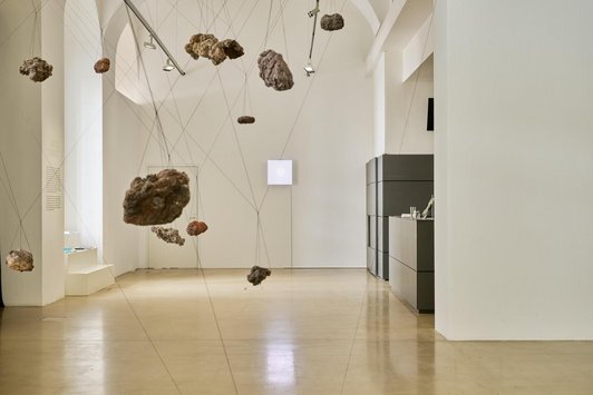 Papiermascheeskulpturen hängen an Schnüren im Raum verteilt.