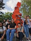 Mädchen sitzen stolz vor einem Sesselturm, den sie als Skulptur zusammengebaut haben.