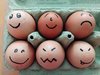 Eier in einem grünen Karton mit gemalten Strich-gesichtern auf jedem Ei.