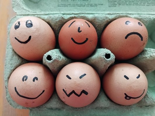 Eier in einem grünen Karton mit gemalten Strich-gesichtern auf jedem Ei.