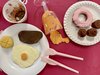 Foto eine Fallenbildes, Geschirr und Besteck, Glas mit ausgeschütteter Flüssigkeit, Essen alles aus recyeltem und bemalten Material – in zufälliger Anordnung auf einem Tisch 