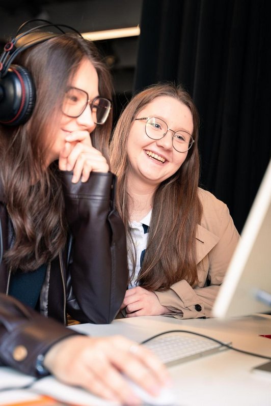 zwei lächelnde Mädchen sitzen an einem Computer
