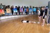 Kind liegt während einer Tanzperformance am Boden und ist mit Bildern auf Stativen umhüllt