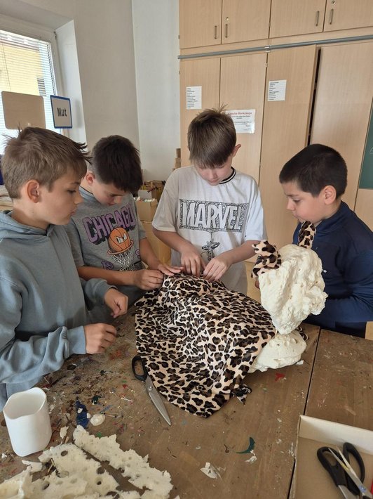 Kinder basten ein §D-Modell aus Stoff mit Leopardmuster.
