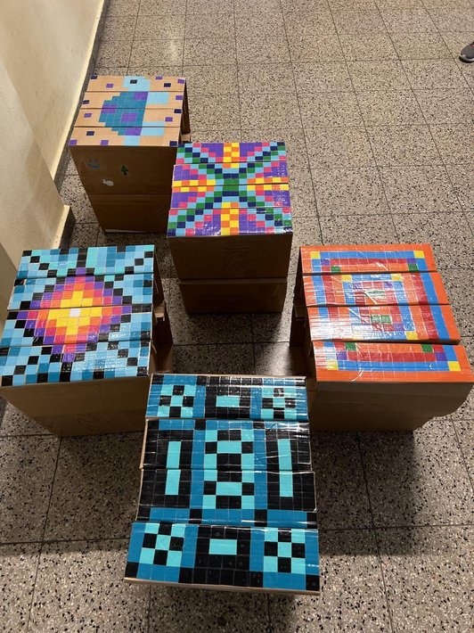 Foto von vier Hockern aus Karton mit Mosaikstücken beklebt.