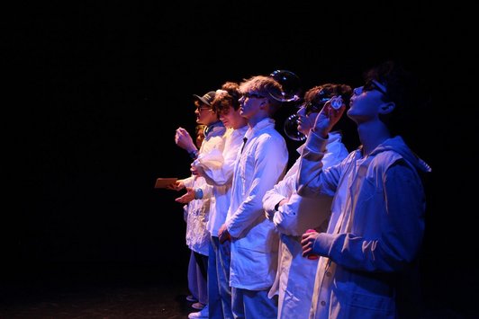 Mit blauem Licht beleuchtete Jugendliche machen Seifenblasen.