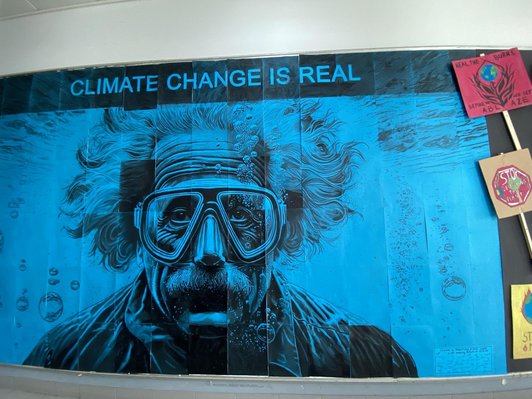 Plakat Blau schwarz, Bild von Albert Einstein mit Taucherbrille unter Wasser. Schriftzug oben Climate Change is Real