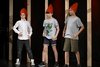 Drei junge Schüler mit roter Zipfelmütze spielen auf einer Bühne.