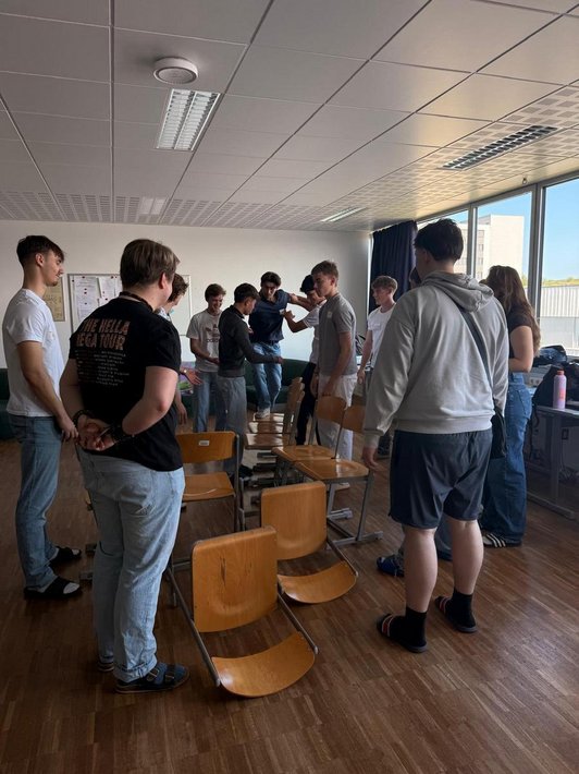 Schüler balancieren auf Stühlen, die am Boden liegen