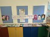 Bunte Portraits mehrerer Kinder liegen auf einem Bord und hängen an der Wand.