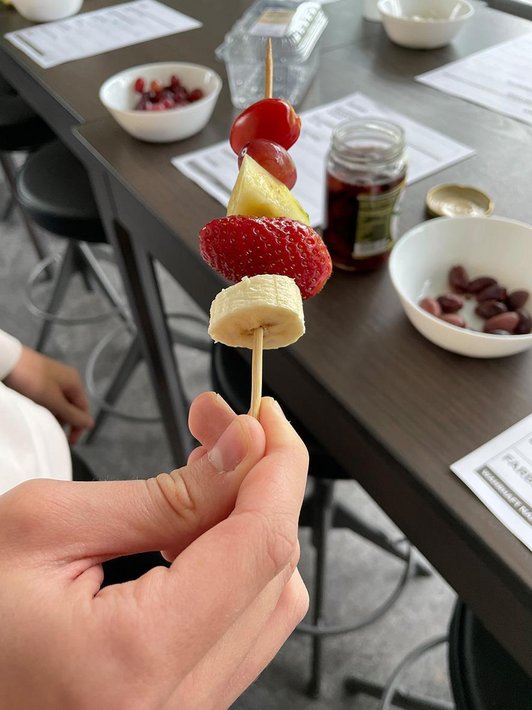 Hand hält Spieß mit Früchten