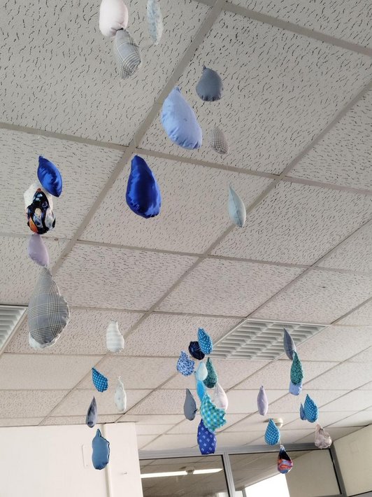 Foto von aus blauen Stoffen genähten Regentropfen die von der Decke hängen.