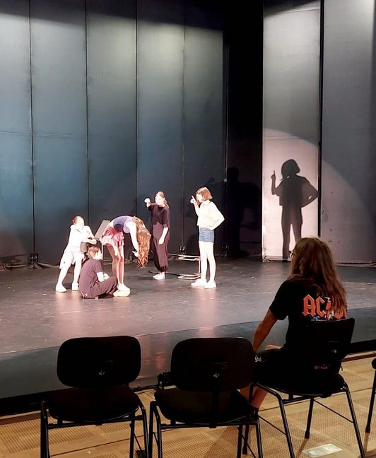 Schülerinnen in Szene auf einer Bühne, ein Mann sieht zu