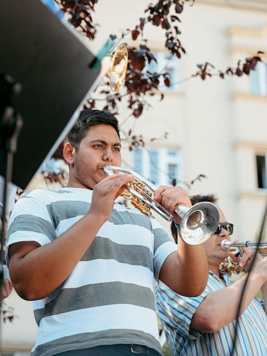 Schüler spielt Trompete, andere Musizierende daneben