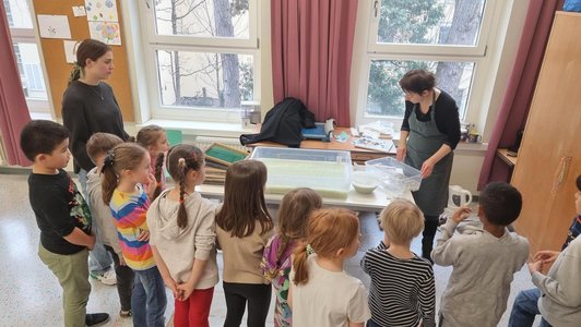 Foto von Kindern die beim Papiermachen zusehen.