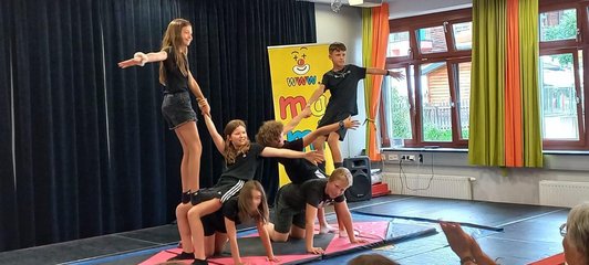 sechs Schüler/innen auf Matten in akrobatischer Gruppenpose