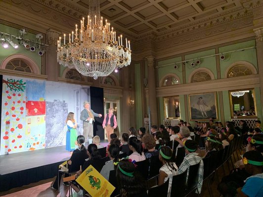 Theateraufführung in einem historischen Gebäude mit Bühne und Zuschauerraum. Auf der Bühne spielen zwei Kinder und ein Erwachsener.