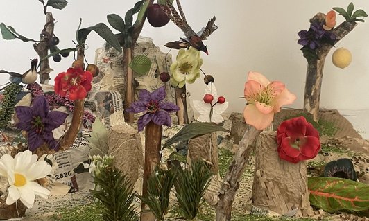 Foto einer Bau einer Kulisse aus Recyclingmaterialien, Papier, Kunstblumen und Holzstücke.