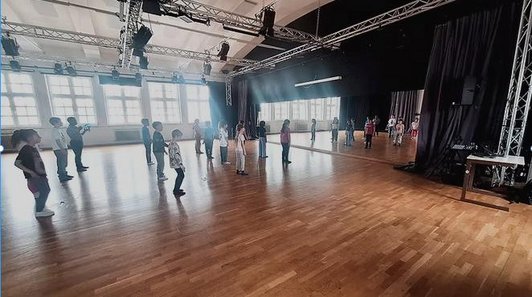 In einem Tanzstudio tanzen Kinder vor einem großen Spiegel.