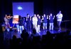 Sechs Schüler/innen klatschen auf eine Bühne in die Hände, eine Violinspielerin begleitet sie und ein Workshopsleiter zeigt ihnen den Rhythmus vor.