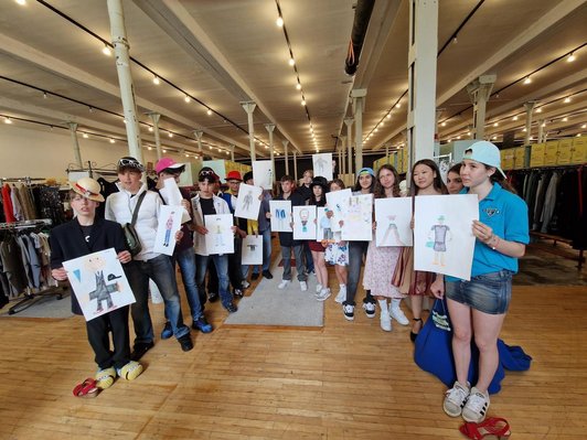 Gruppe von Schüler/innen in hält Zeichnungen von Personen der Kamera entgegen
