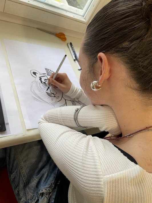 Schülerin zeichnet Portrain, halb Mensch halb Tiger