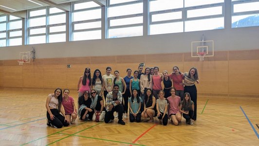 Gruppe von Schüler/innen und Mann posieren in Turnsaal für Kamera