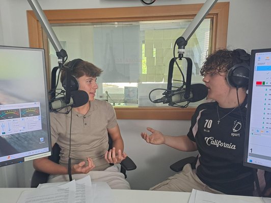 Zwei Schüler moderieren in ein Micro, sie haben viel Spaß dabei