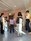 Mädchen stehen mit dem Rückenzugewandt vor einer Künstlerin im Gang der Schule.