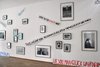 Foto einer Wand der Ausstellung mit gerahmten Fotografien und Spruchbändern